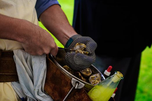 closeup of the hand of a man with a chainmail glove chucking an oyster