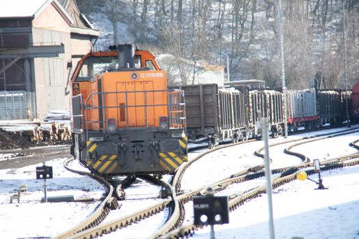 orange diesel locomotive pulls its train through the winter landscape