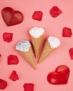 two red hearts, ice creams and rose petals on pink background