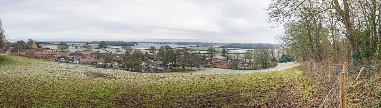 Panoramic view over rural countryside farming landscape with fields in a valley during winter frost