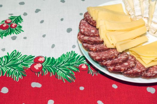 a plate of slicing cheeses and sausages on a New Year's tablecloth. High quality photo