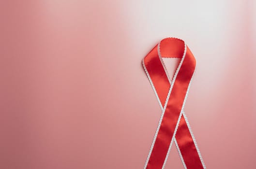 red ribbon for AIDS day on a red background. the view from the top. High quality photo