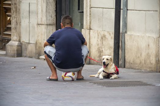 terni,italy august 16 2020:man sitting on the balloon and near his labrador dog