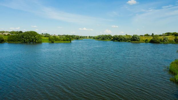 Scenic aerial view of river and green fields in Russian countryside. Natural landscape of the river curve and lush green trees.