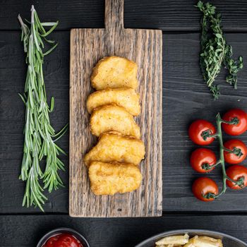 Nuggets breaded on black wooden background, flat lay.