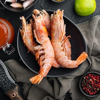 Raw red Argentinian prawns set in bowl, on black background, top view flat lay