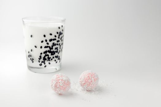 pink chocolate candy and a glass of milk on a white background. candy ball macro. isolate. High quality photo