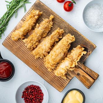 Crispy chicken sticks meat on white background, flat lay.