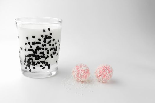 pink chocolate candy and a glass of milk on a white background. candy ball macro. isolate. High quality photo