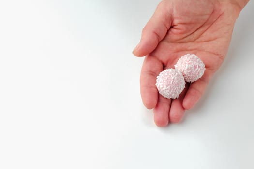 pink chocolate candy in hand on a white background. candy ball macro. isolate. High quality photo