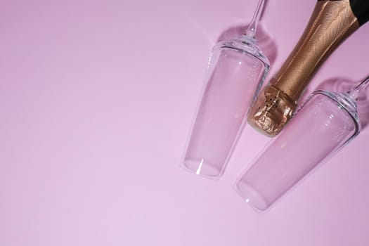 bottle of champagne with glasses on a pink background. high-quality photos