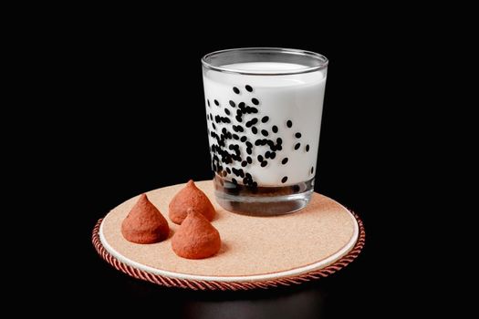 aa glass of milk and a truffle candy on a black background. health food. isolate glass of milk and a truffle candy on a black background. health food. isolate. High quality photo