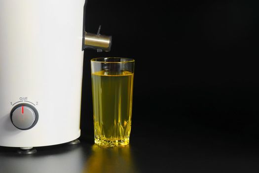 a glasa glass of juice and a juicer on black backgrounds of juice and a juicer on black background. High quality photo