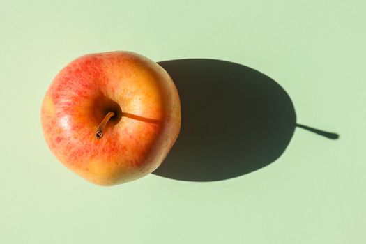 an Apple with a hard shadow on a plain background. the view from the top. blank for the pattern. High quality photo