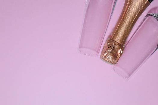 bottle of champagne with glasses on a pink backgroun . High quality photo