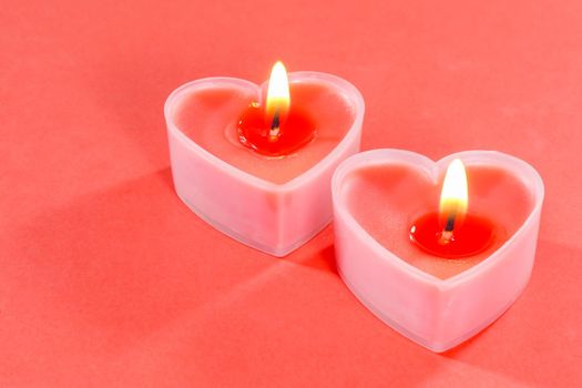 pink candles in the form of a heart on a red background for Valentine's day . High quality photo