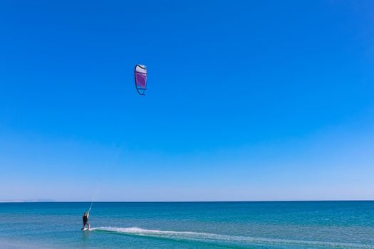 a kitesurfer surfing on the smooth azure water. recreational sport. A Man Rides A Kiteboarding In The Sea Water. extreme sport. High quality photo