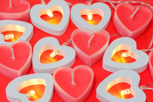 pink candles in the form of a heart on a red background for Valentine's day . High quality photo