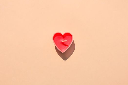 heart-shaped candle on a brown background. hard shadow. isolate. High quality photo