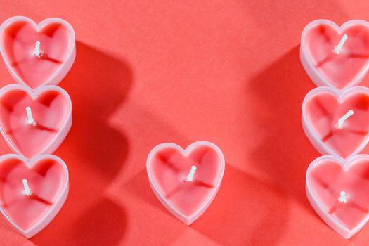 pink candles in the form of a heart on a red background for Valentine's day . High quality photo