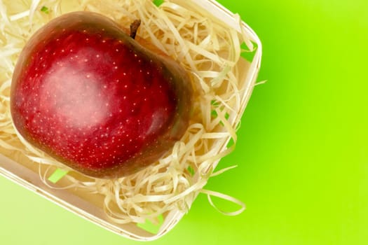 red Apple in a basket on a green background close-up. High quality photo