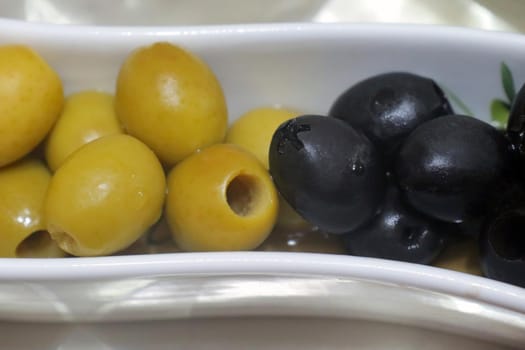 green and black pitted olives on the same dish macro