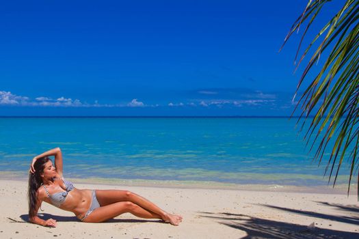 Woman in bikini laying on tropical beach
