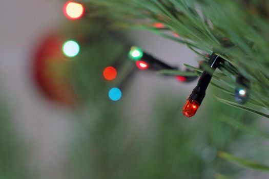 a luminous garland on a Christmas tree branch as a bokeh background