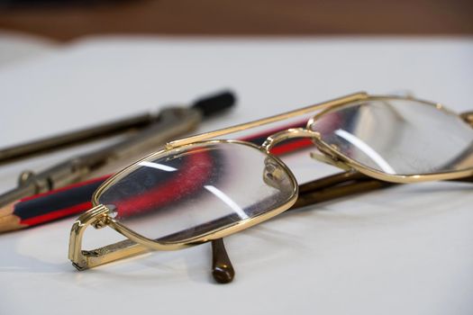 Glasses and drawing supplies are on the table in the school classroom. University academic subjects for geometry.Ruler, compass, pencil and glasses on a white background.