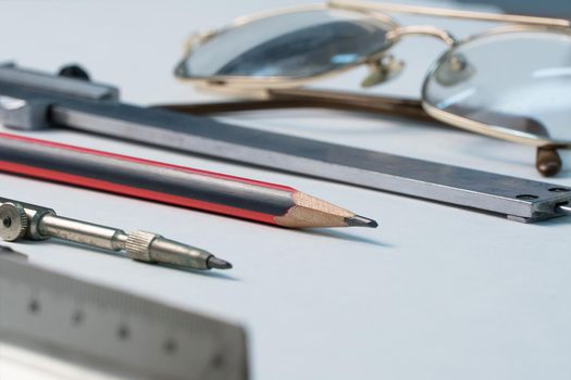 Glasses and drawing supplies are on the table in the school classroom. University academic subjects for geometry.Ruler, compass, pencil, caliper and glasses on a white background.