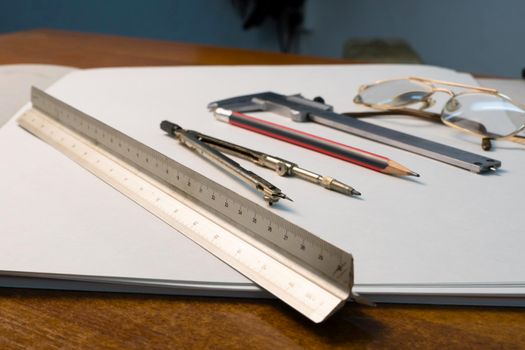 Glasses and drawing supplies are on the table in the school classroom. University academic subjects for geometry.Ruler, compass, pencil, caliper and glasses on a white background.