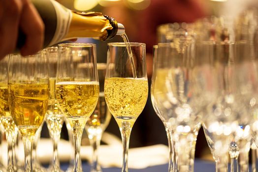 Bartender pouring champagne into glasses at party.