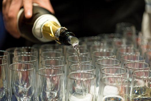 Bartender pouring champagne into glasses at party.