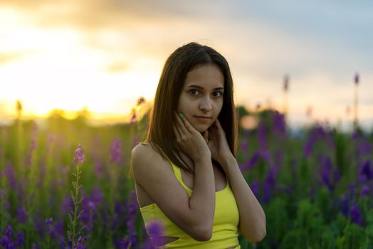 beautiful girl in yellow dress  standing in a field of lupine flowers