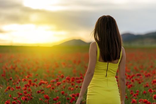 Woman in yellow dress standing in field of poppies