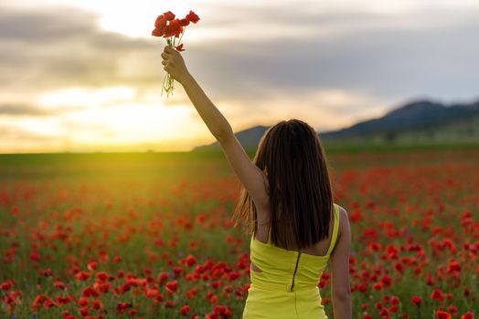 Woman in yellow dress standing in field of poppies