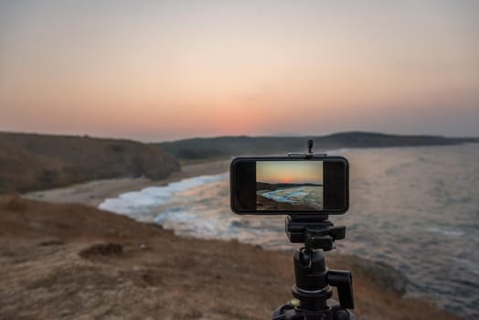 Cell technology and vacation. Close up of smartphone, taking picture of sea sunset.