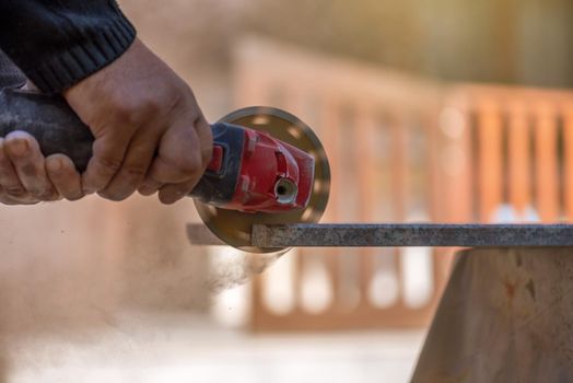 Grinder worker cuts stone block with electric hand saw.