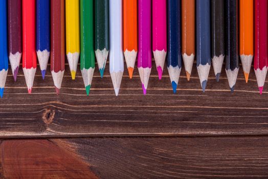 Colored multi colored pencils close up macro down on a vintage wooden background.