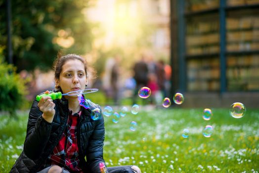 Young spring fashion casual woman blow bubbles in the sunset