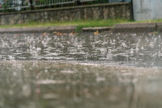 heavy rain drops falling on city asphalt during downpour in autumn