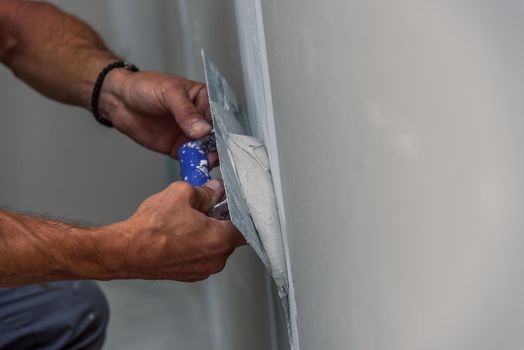 old manual worker with wall plastering tools renovating house. Plasterer renovating indoor walls and ceilings with float and plaster.