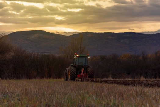 Tractor plowing fields at sunset.