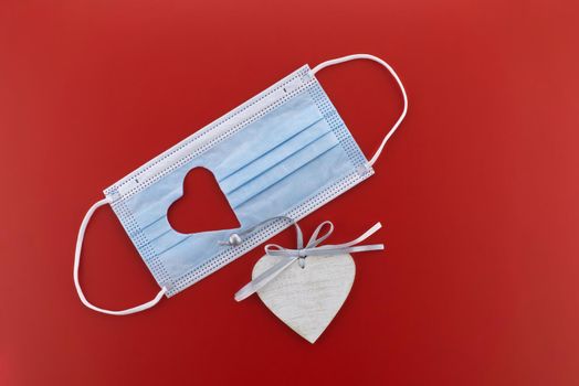 Face mask with a cut-out heart shape over red background with free copy space
