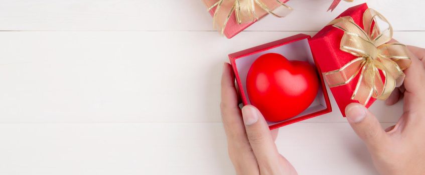 Valentine day, hand open red gift box with heart shape on wooden white background, celebration and anniversary with giving love, presents with romantic and surprise, holiday and festive concept.