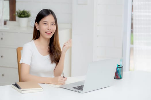 Young asian woman confident working at home with laptop computer and thinking idea for planning, freelance happy girl excited and success using notebook thoughtful and writing, business concept.