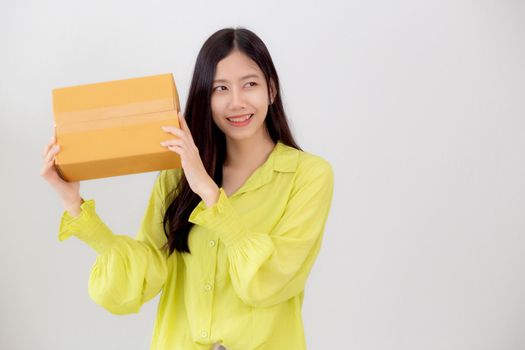 Young asian woman smiling and holding cardboard box with surprise at home, happy female carrying parcel box with excited, present and gift, packaging for deliver, online shopping store and service concept.