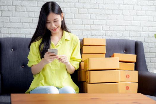 Young asian woman is entrepreneur check order from smartphone with customer while purchase online, logistic and delivery, online shopping, female is seller of business SME, merchant looking phone.
