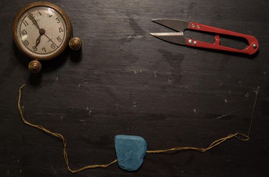 Black background with sewing utensils and a clock