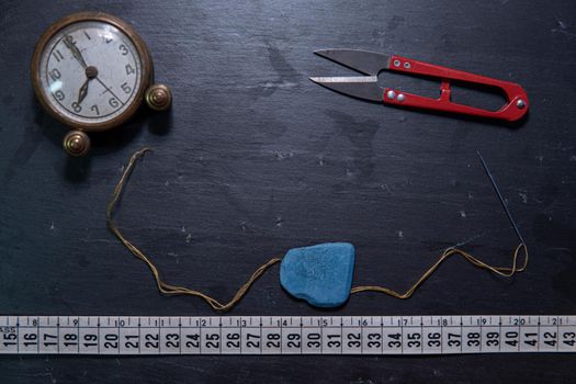 Black background with sewing utensils and a clock